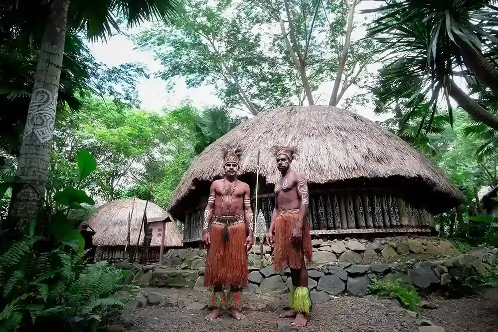 Papuan hosts in traditional dress outside a village house